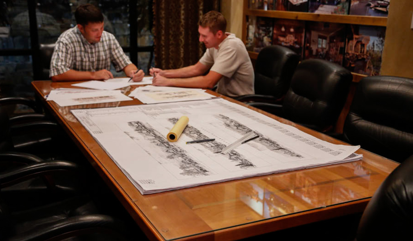 Two men reviewing building construction plans at a big table