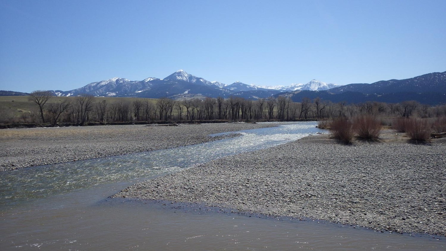 Yellowstone River flowing through rocky banks with mountains in the background