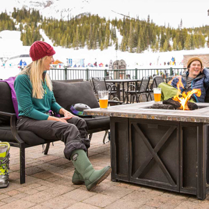 Three friends sitting around on an outdoor patio at a ski resort.
