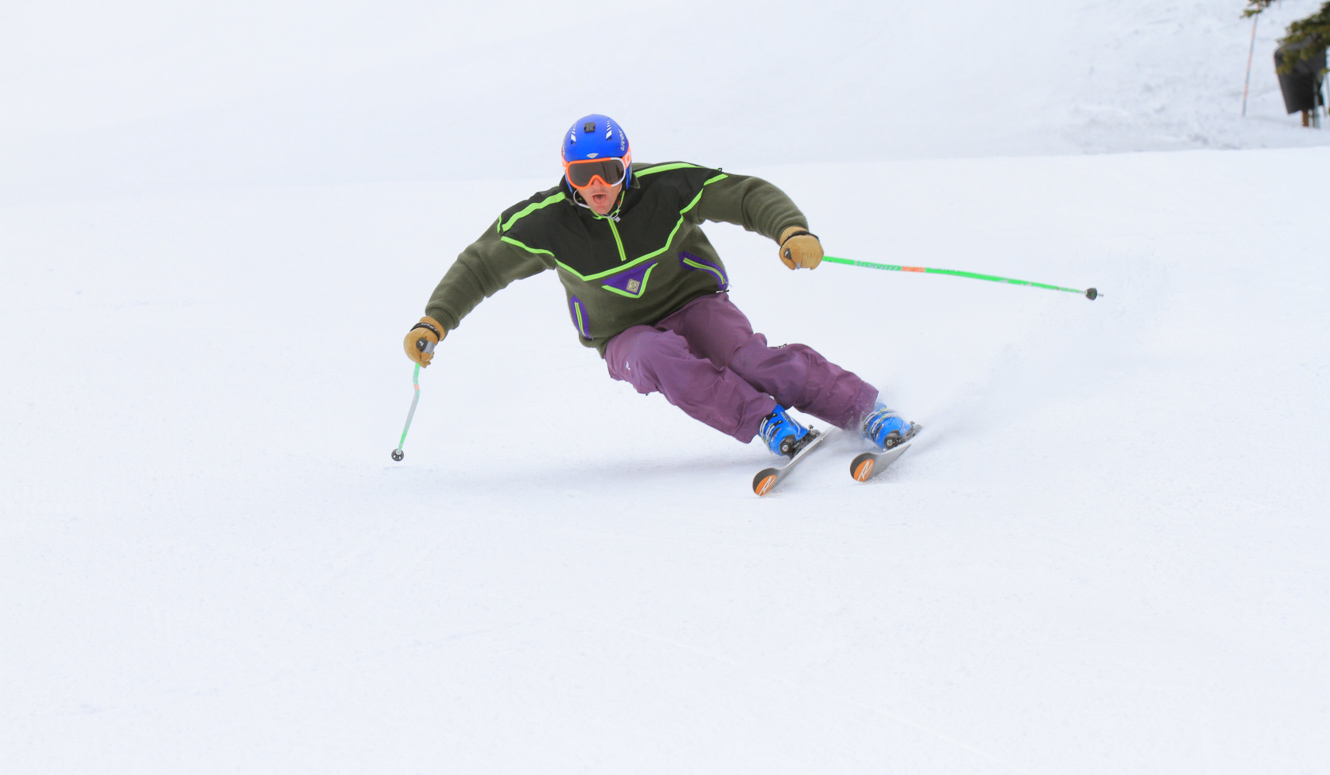 Downhill skier racing down a groomed slope