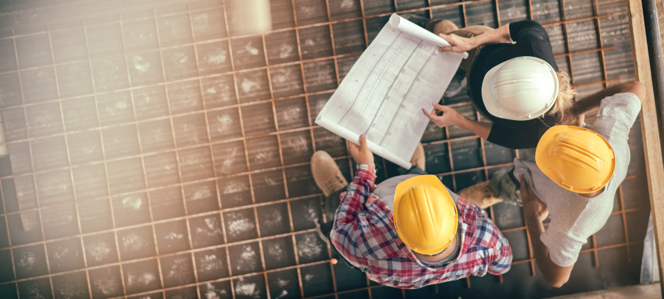 Overhead shot of people on a construction site. They are looking over blueprints.