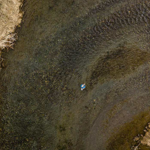 Aerial view of a fly fisherman standing in a river.