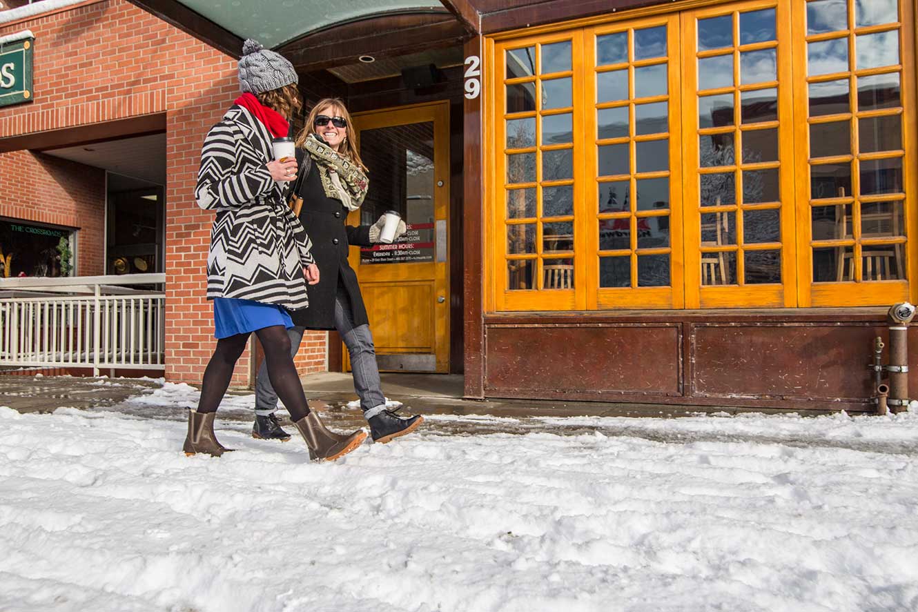 Main street store front with two women walking and talking.