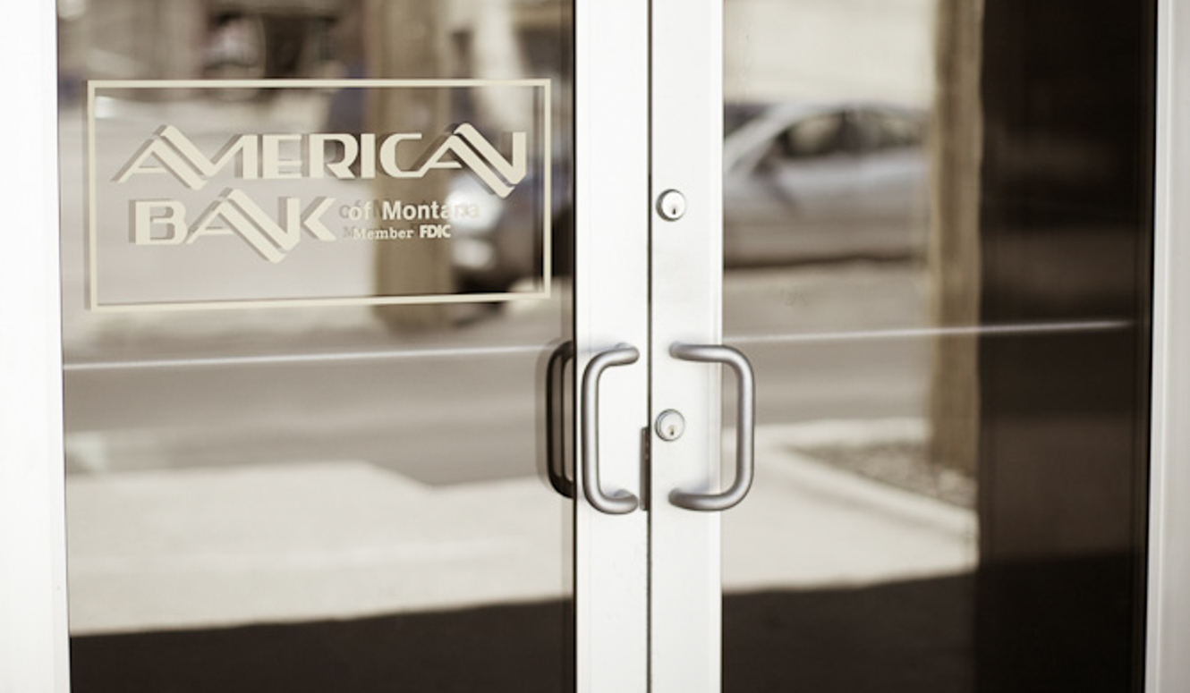 Closed glass doors with American Bank logo decal